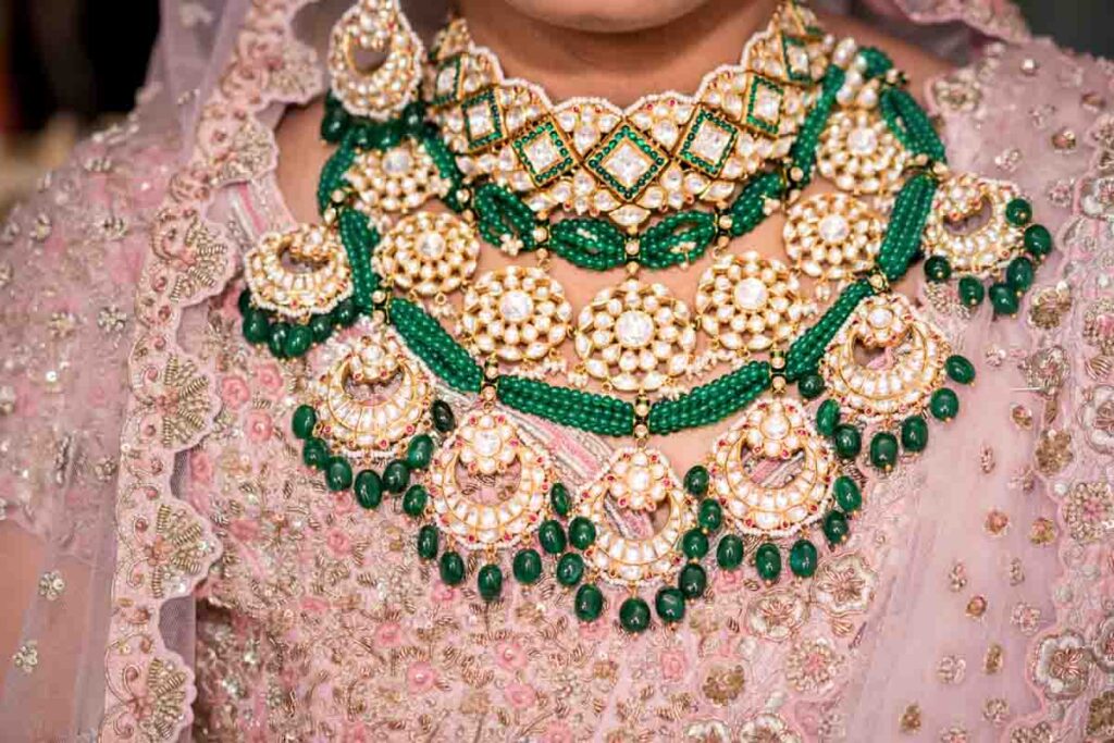 Closeup of an emerald and pearl bridal necklace on a pink lehenga