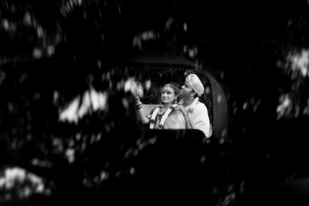 Couple embraces outdoors at night framed through blurred foreground leaves