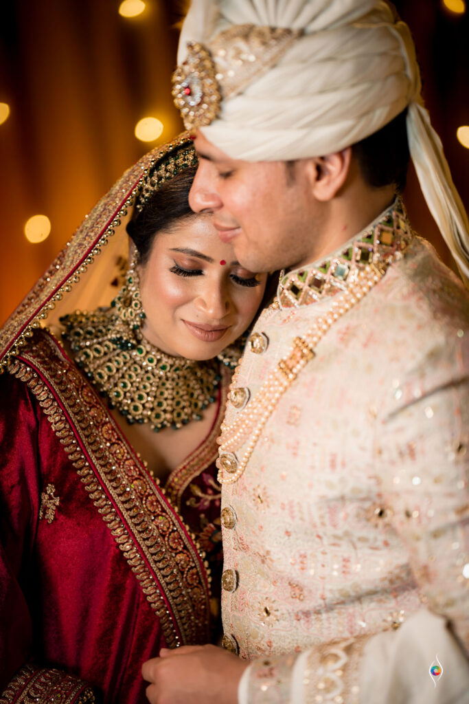 Groom kisses the bride on the forehead amid warm bokeh lights
