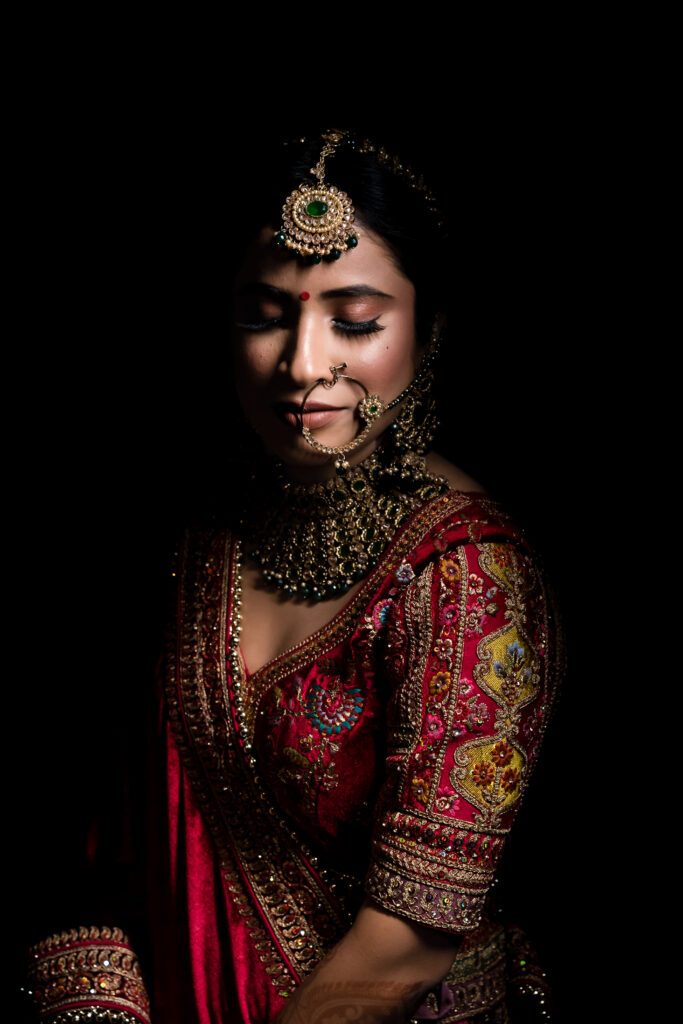 Bride portrait in dramatic low light wearing a red blouse and gold jewelry