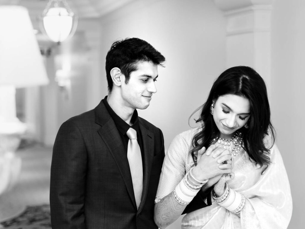 Black and white photo of a couple admiring bridal bangles indoors