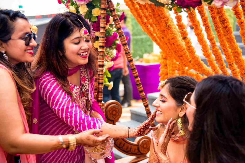 Bride greets smiling guests under an orange and pink floral canopy