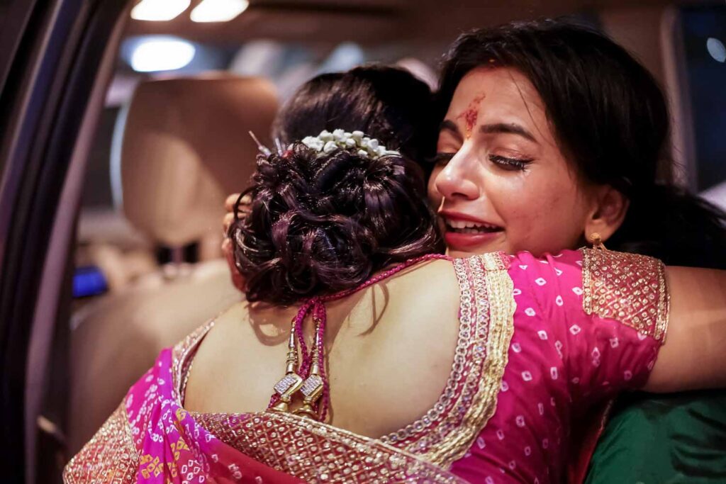 Two women embrace tearfully inside a car during an emotional farewell moment