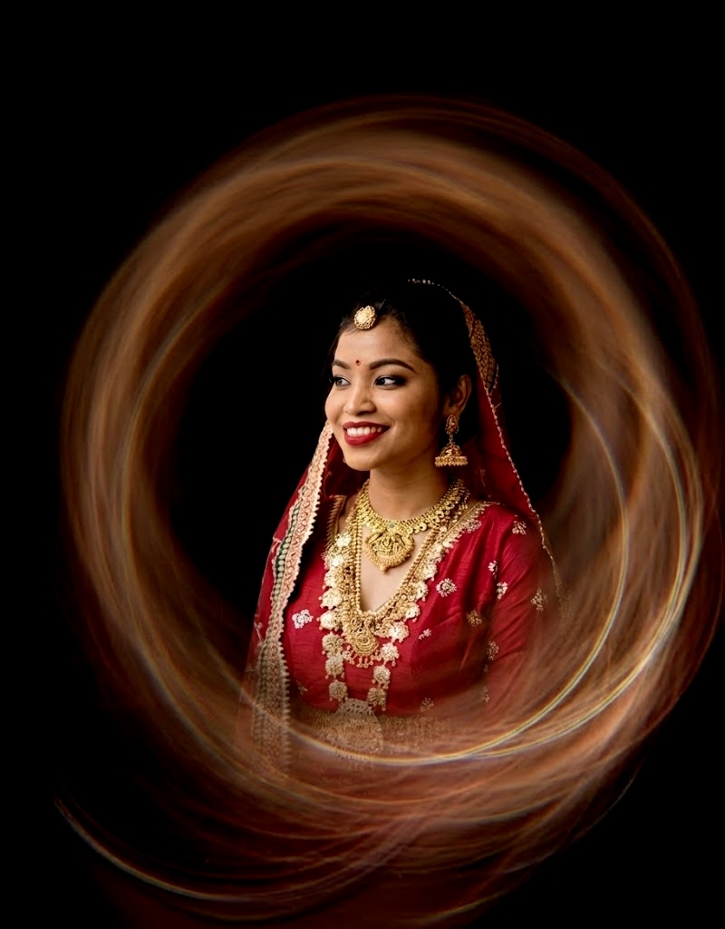 Bride portrait with a circular light trail effect around red lehenga and jewelry