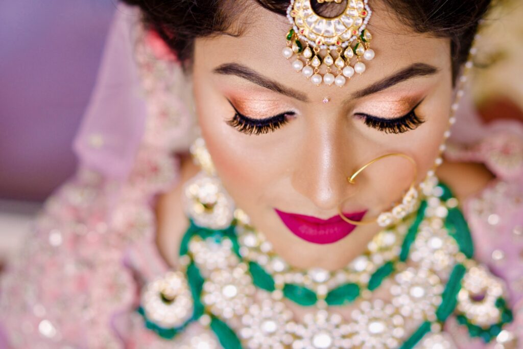 Closeup of a bride with closed eyes wearing emerald and gold jewelry