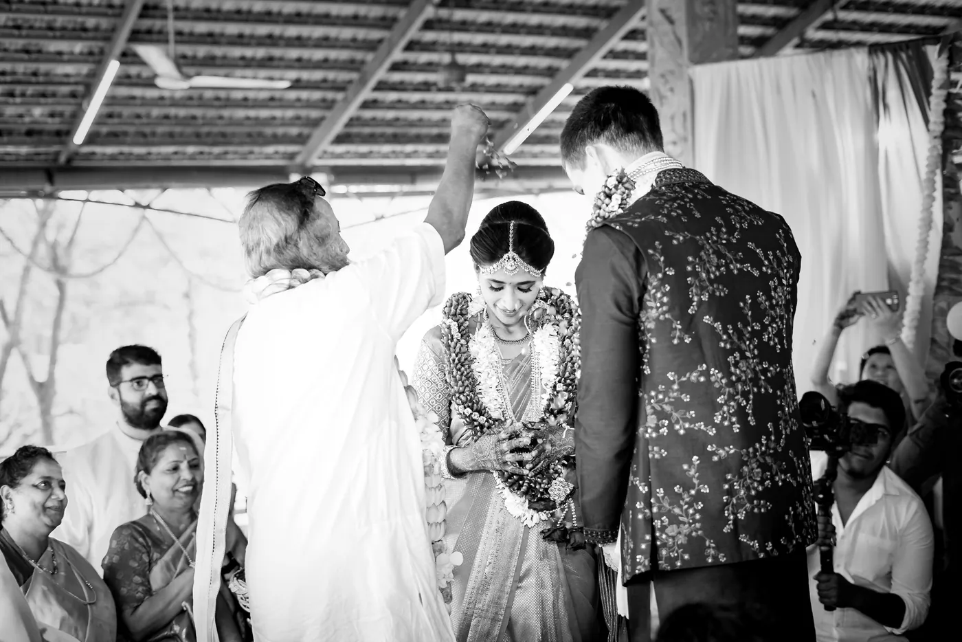 Black and white of Sri Sri Ravi Shankar raising his hand in blessing over Medha and Stefan