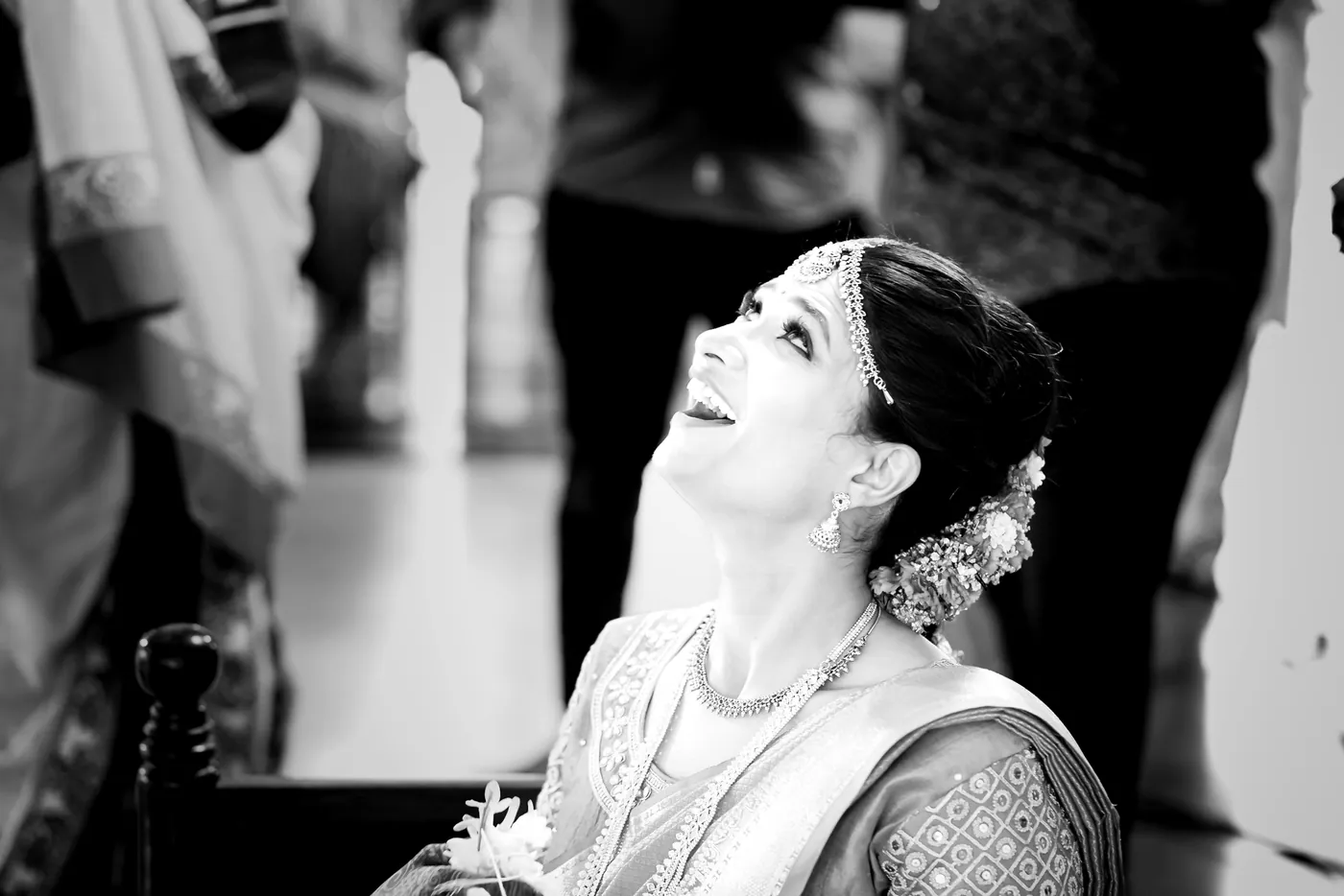 Black and white of Medha laughing as she looks up with a flower garland