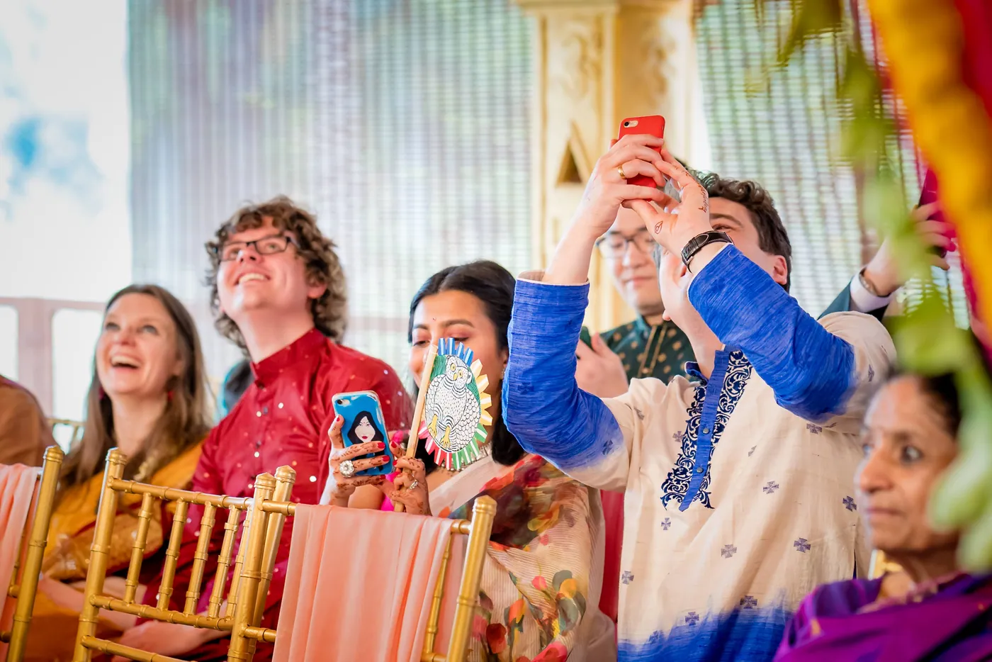 Guests laugh and film on their phones as the ceremony begins