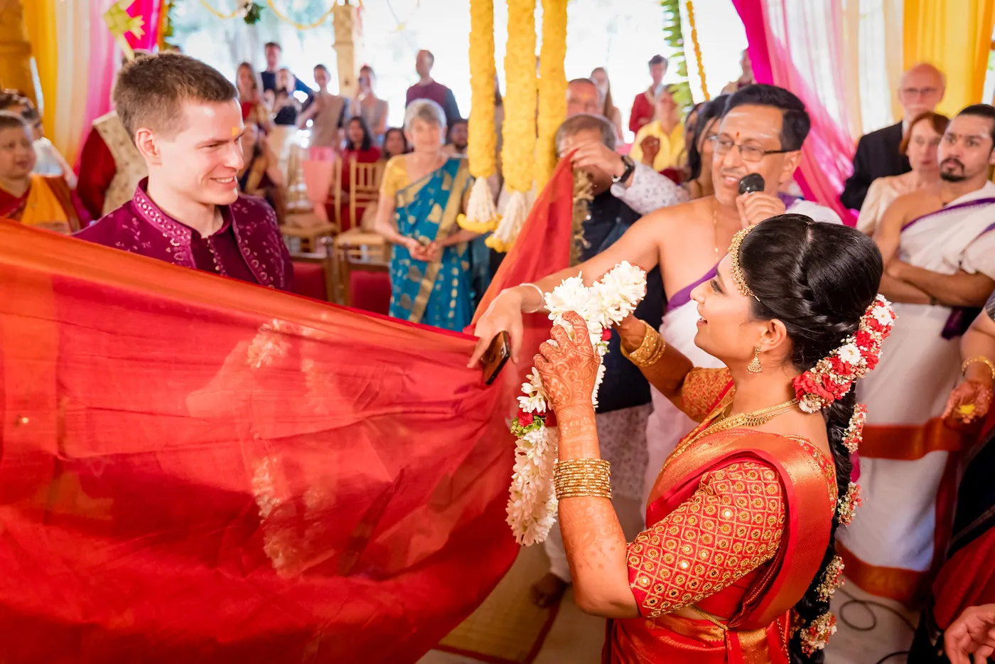 The red cloth is lowered as Medha and Stefan face each other with garlands among guests