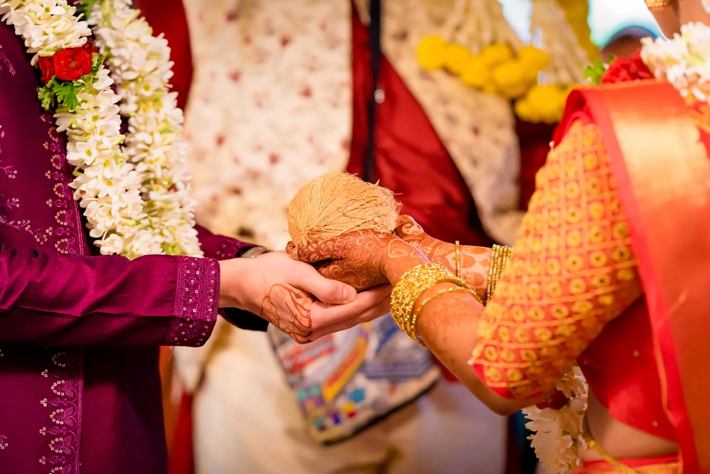 Stefan and Medha exchange a coconut with hands joined, their jasmine garlands touching