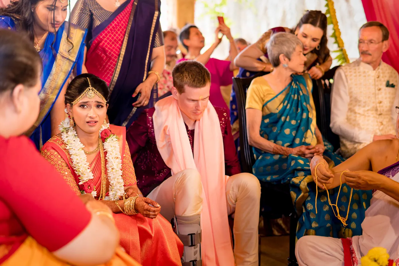 Medha looks emotional in garlands as Stefan sits beside her and women reach in to bless them