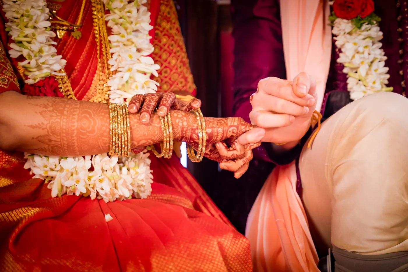 Medha's hand with a ring and henna is held among white garlands