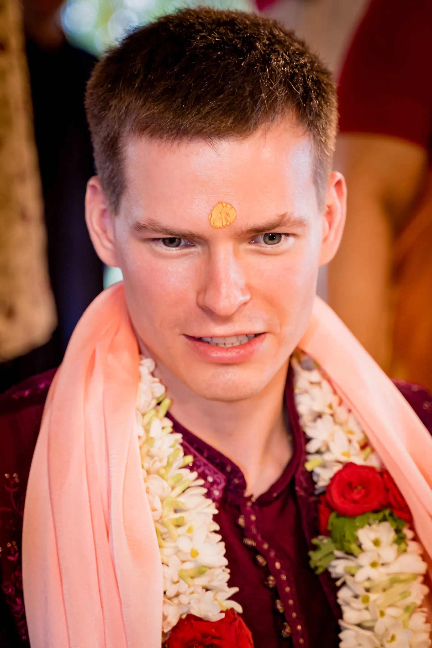 Stefan with a yellow mark on his forehead looks thoughtfully ahead in a jasmine garland and pink shawl