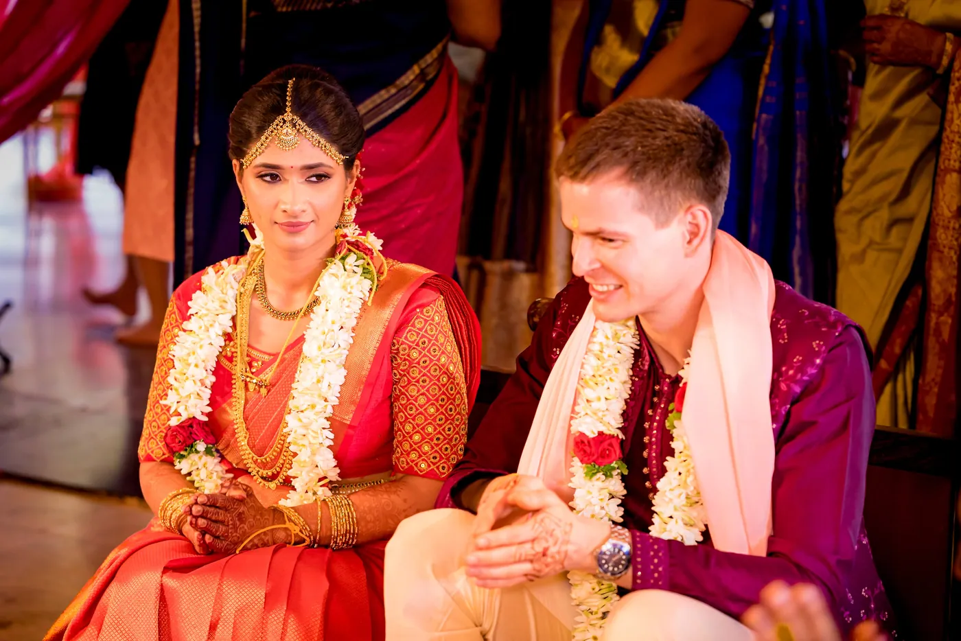 Medha and Stefan sit side by side in garlands, both smiling and glowing