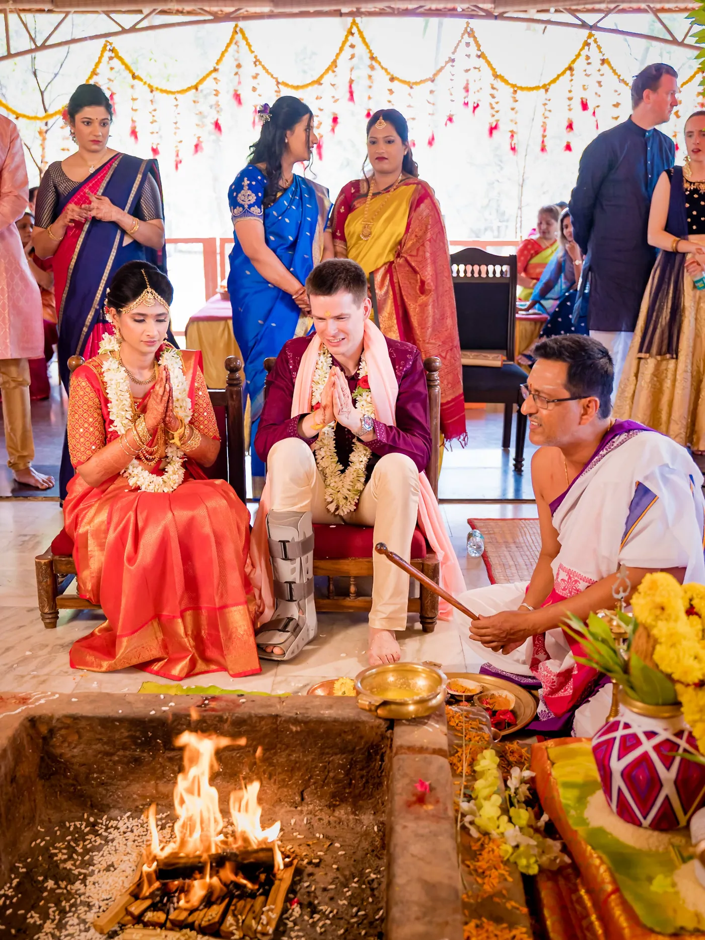 Medha and Stefan perform a ritual with a priest beside the burning sacred fire