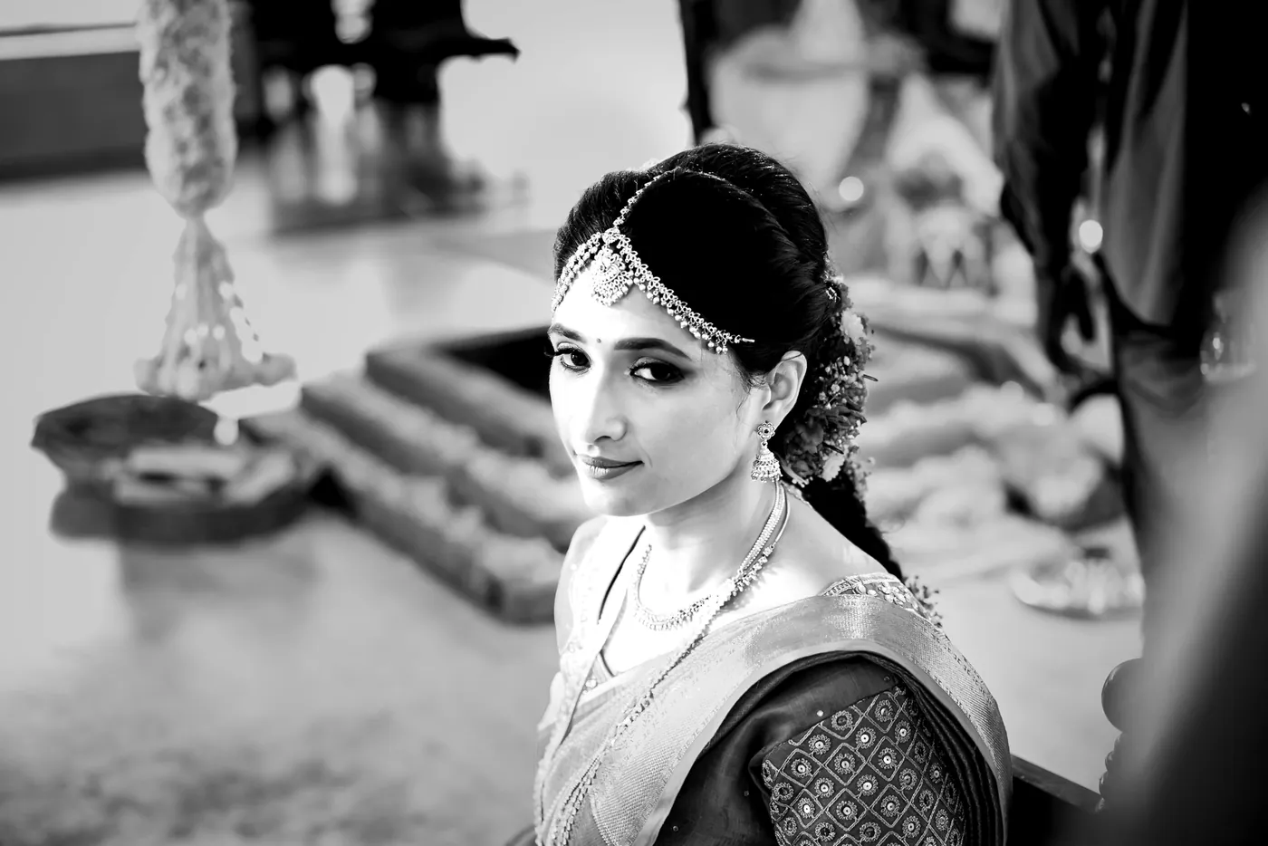 Black and white of Medha seated near a lamp and steps, glancing back over her shoulder
