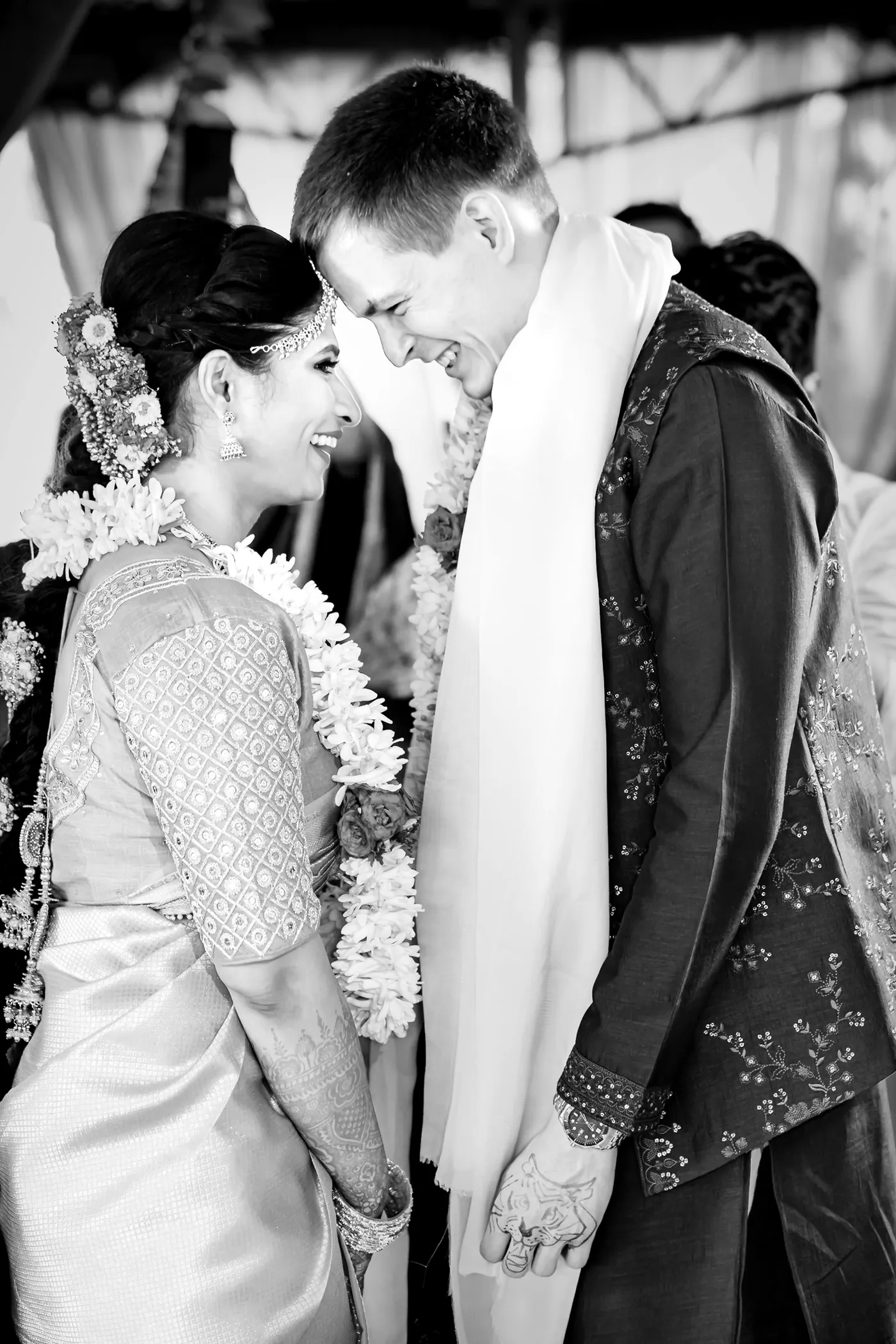 Black and white of Medha and Stefan touching foreheads in jasmine garlands, his face tilted toward hers