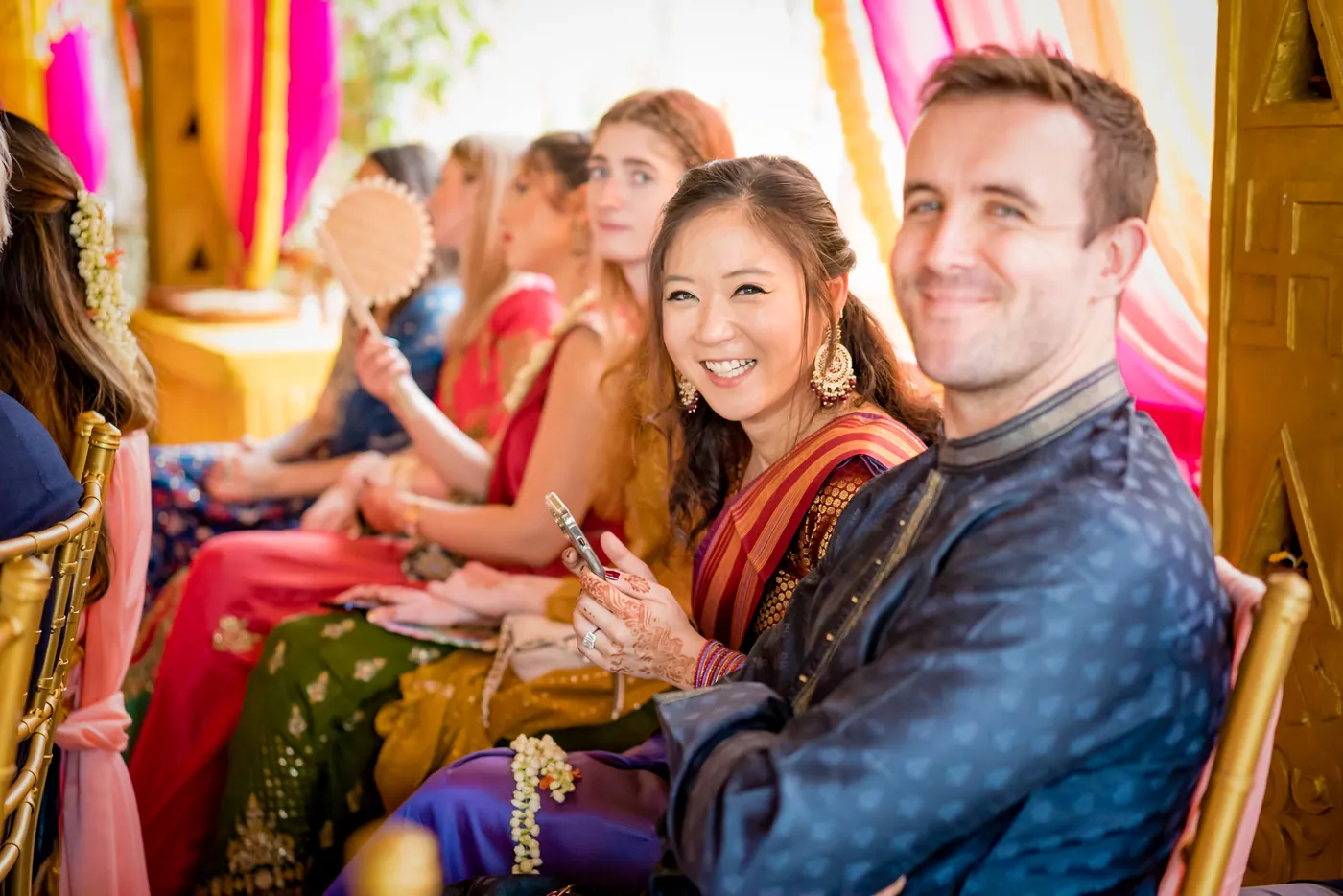 Two guests from abroad smile as they watch the ceremony, a man in blue and a woman in red