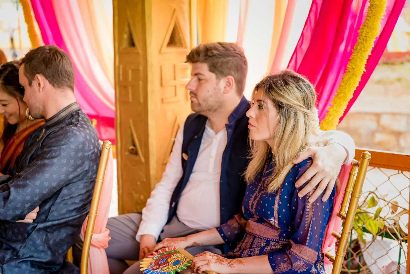 A couple of guests sit close together at the ceremony, the man in a navy jacket