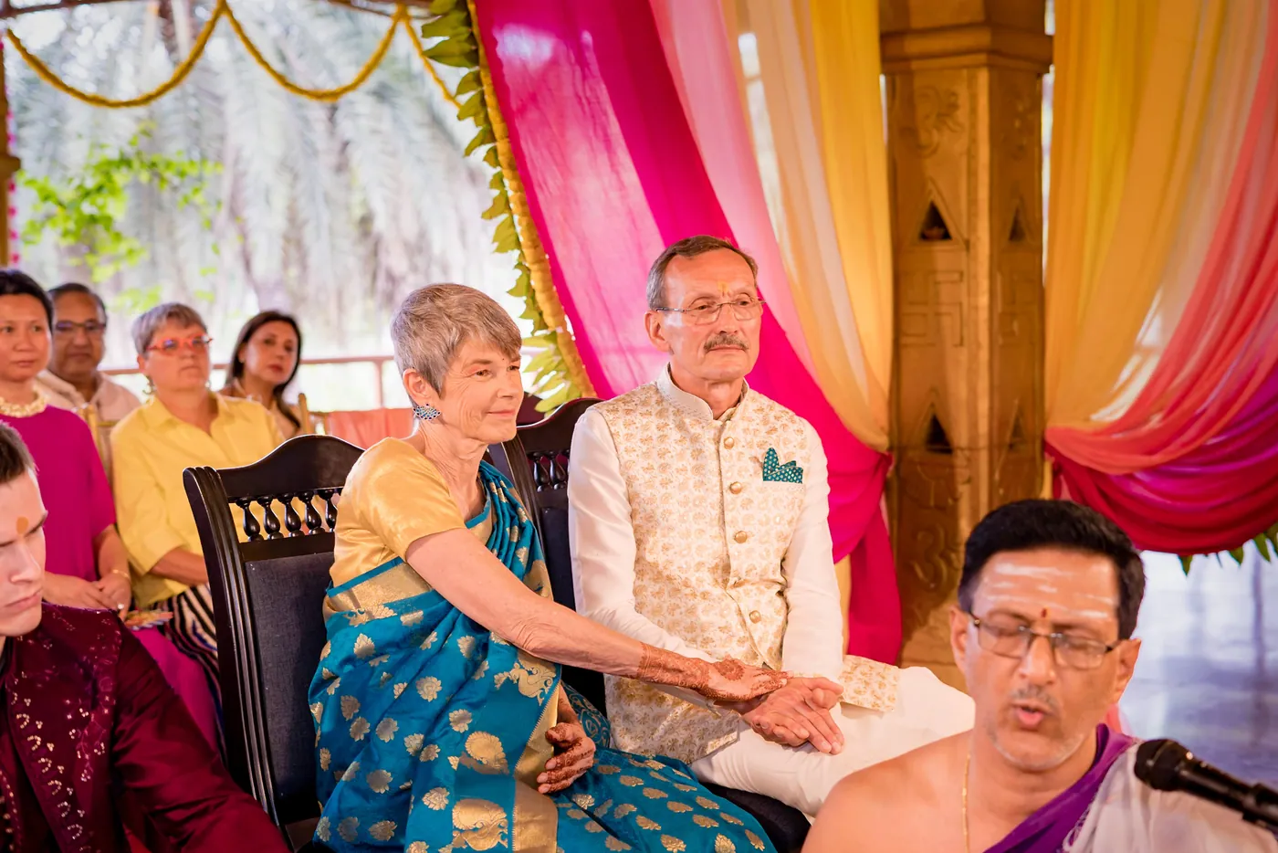 Stefan's parents sit beside a priest with a microphone during the ceremony