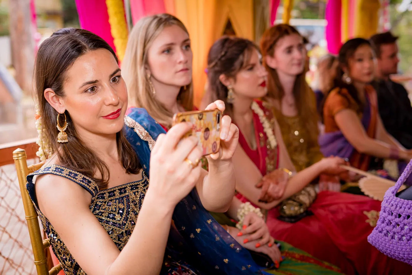 A woman holds a phone to photograph the ceremony among guests sitting beside her