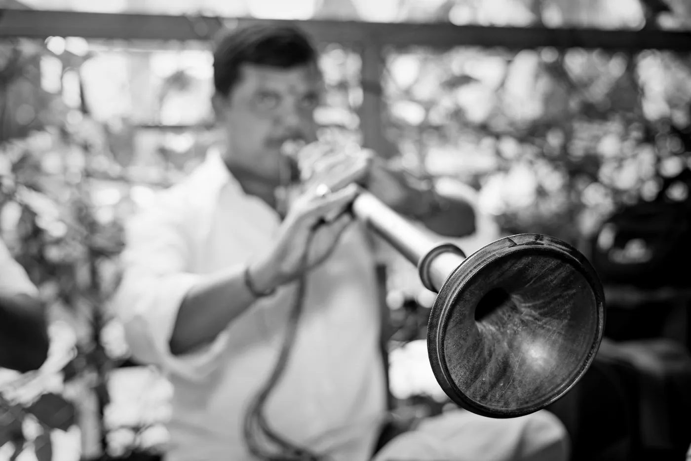 Black and white of a man blowing a long brass horn at the ceremony