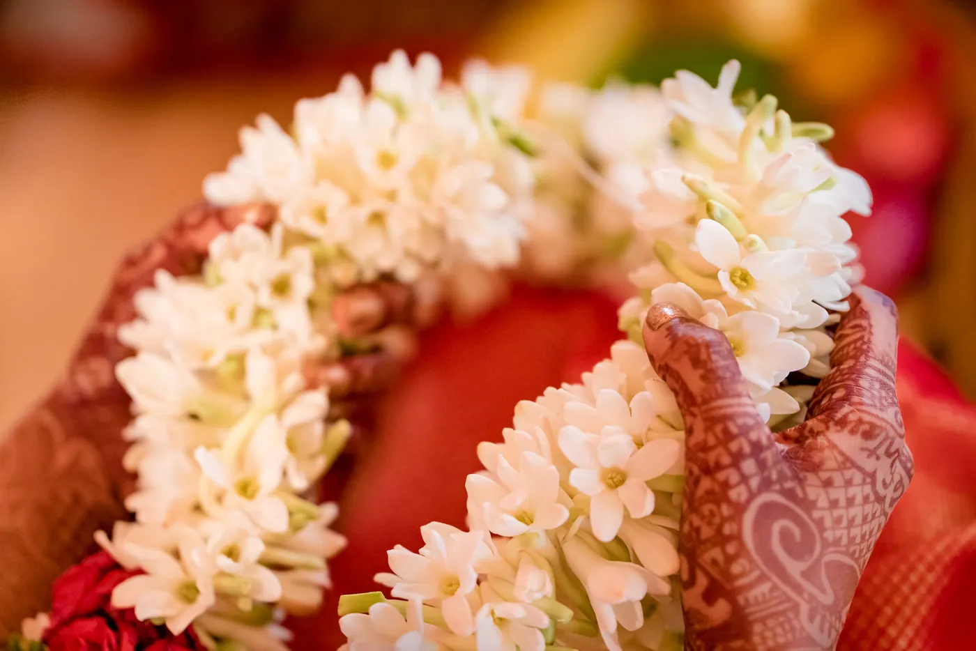Close view of a white jasmine garland held in a henna-covered hand