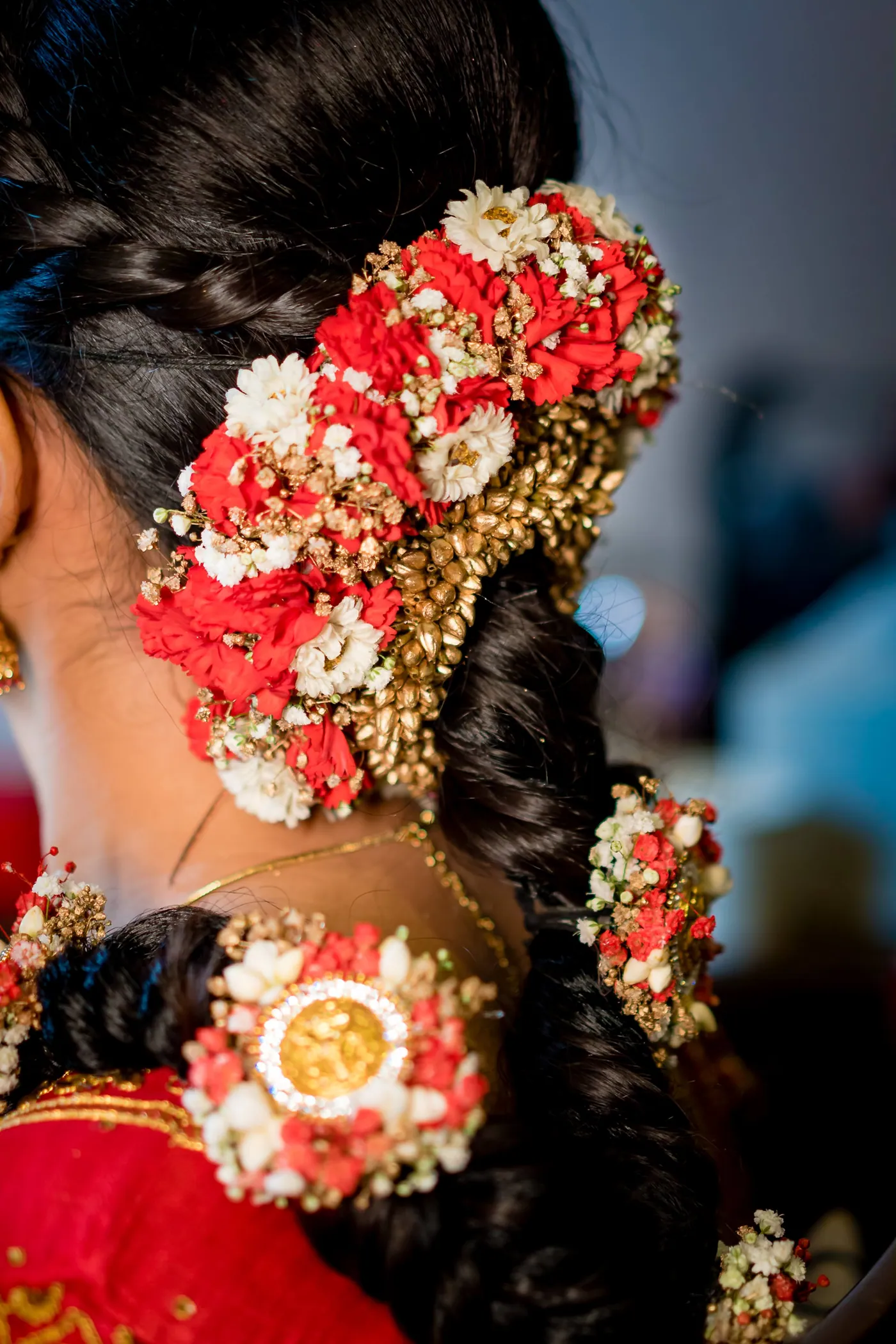 Close view of Medha's braided hair covered in red and white flowers and gold ornaments