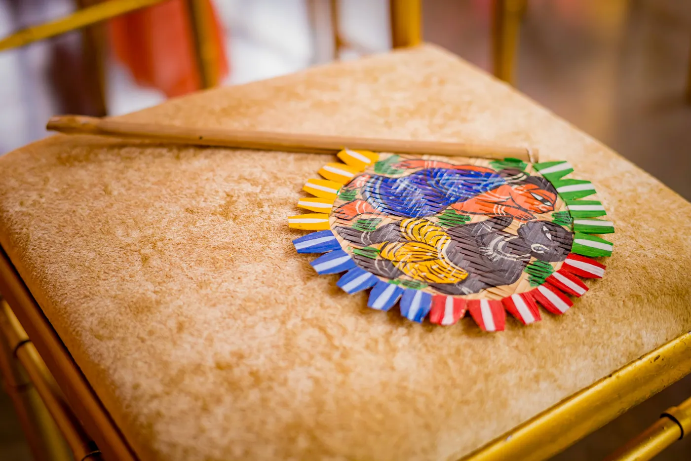 A painted floral coaster rests on a woven stool with a pair of sticks