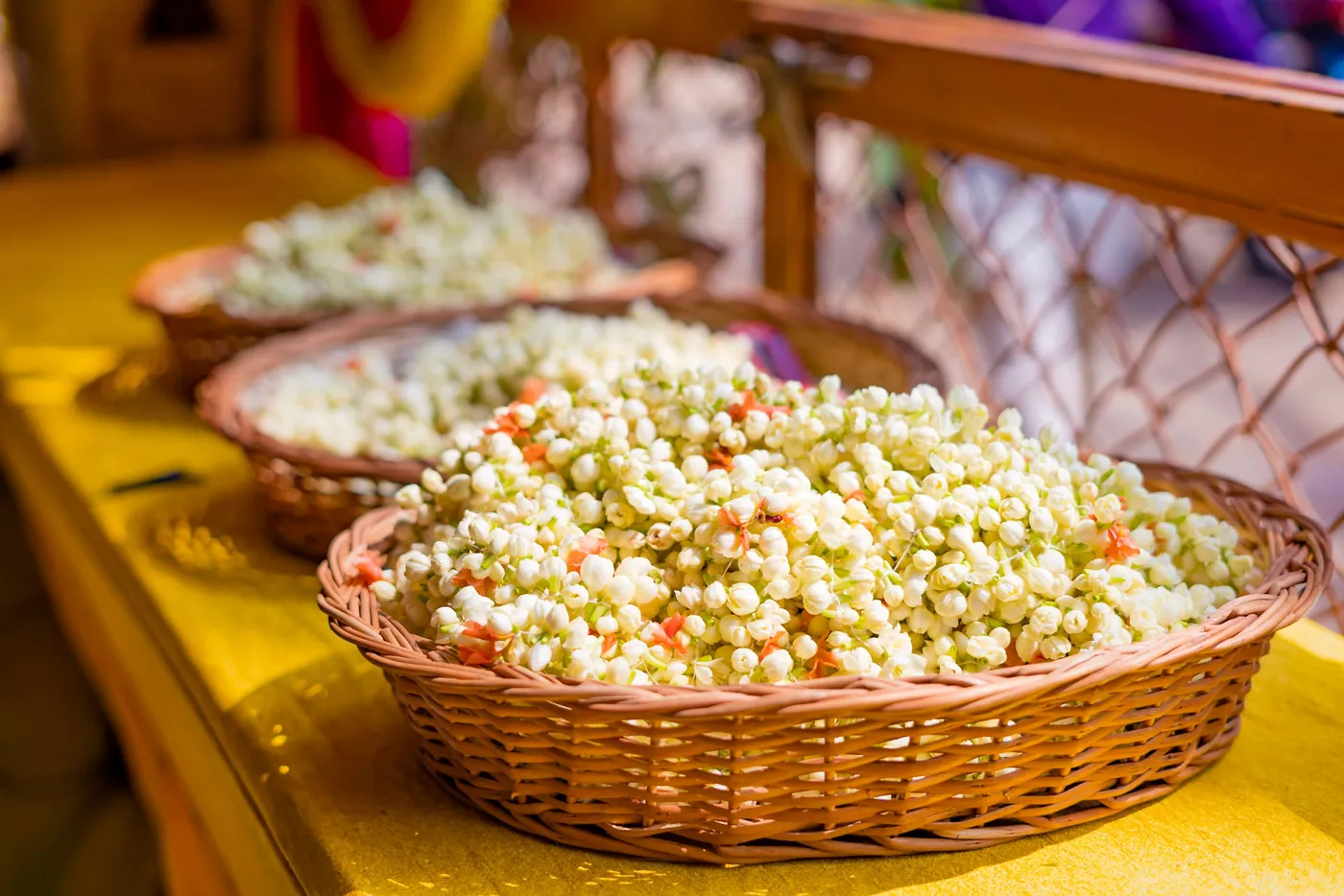 Baskets of white jasmine flowers sit on a yellow cloth table