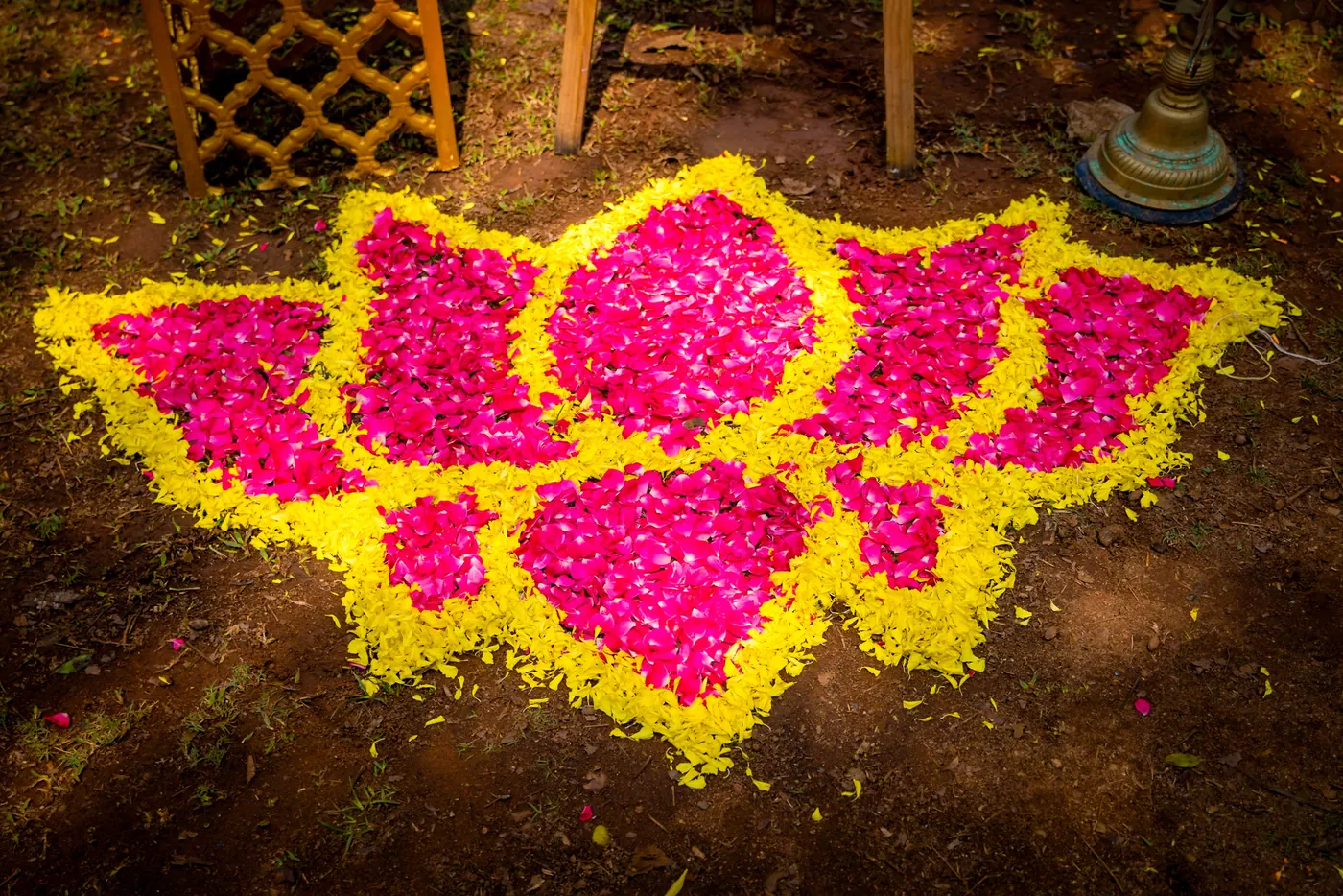 A lotus design made of pink and yellow flower petals lies on the ground