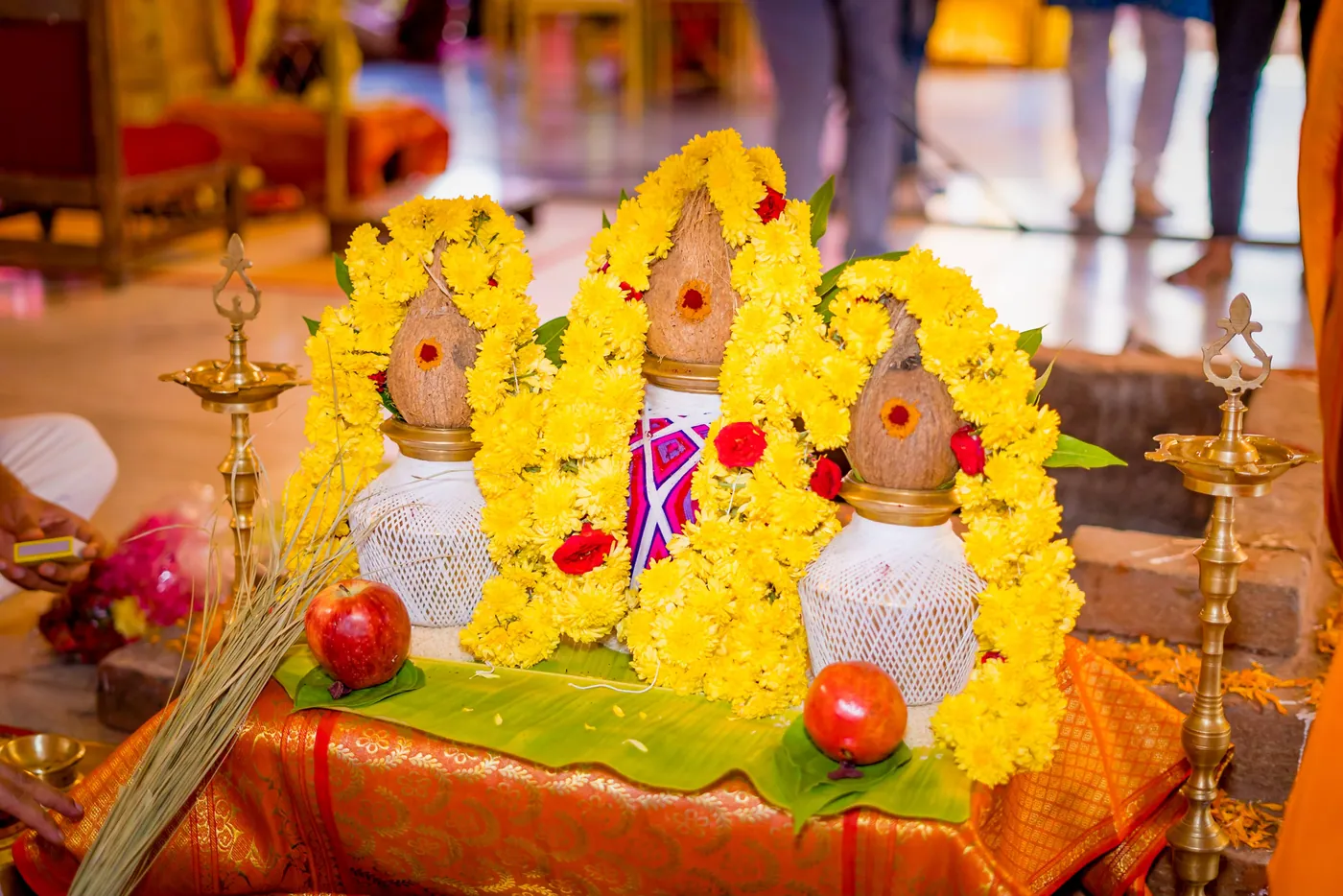 Three decorated oil lamps with yellow flower garlands sit on a ceremonial tray