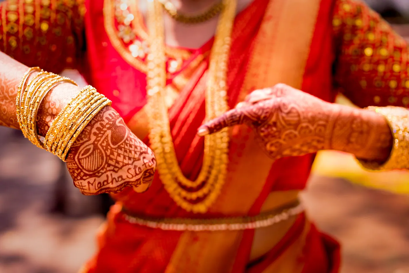Medha points to her hand, where the names Medha and Stefan are written into her henna