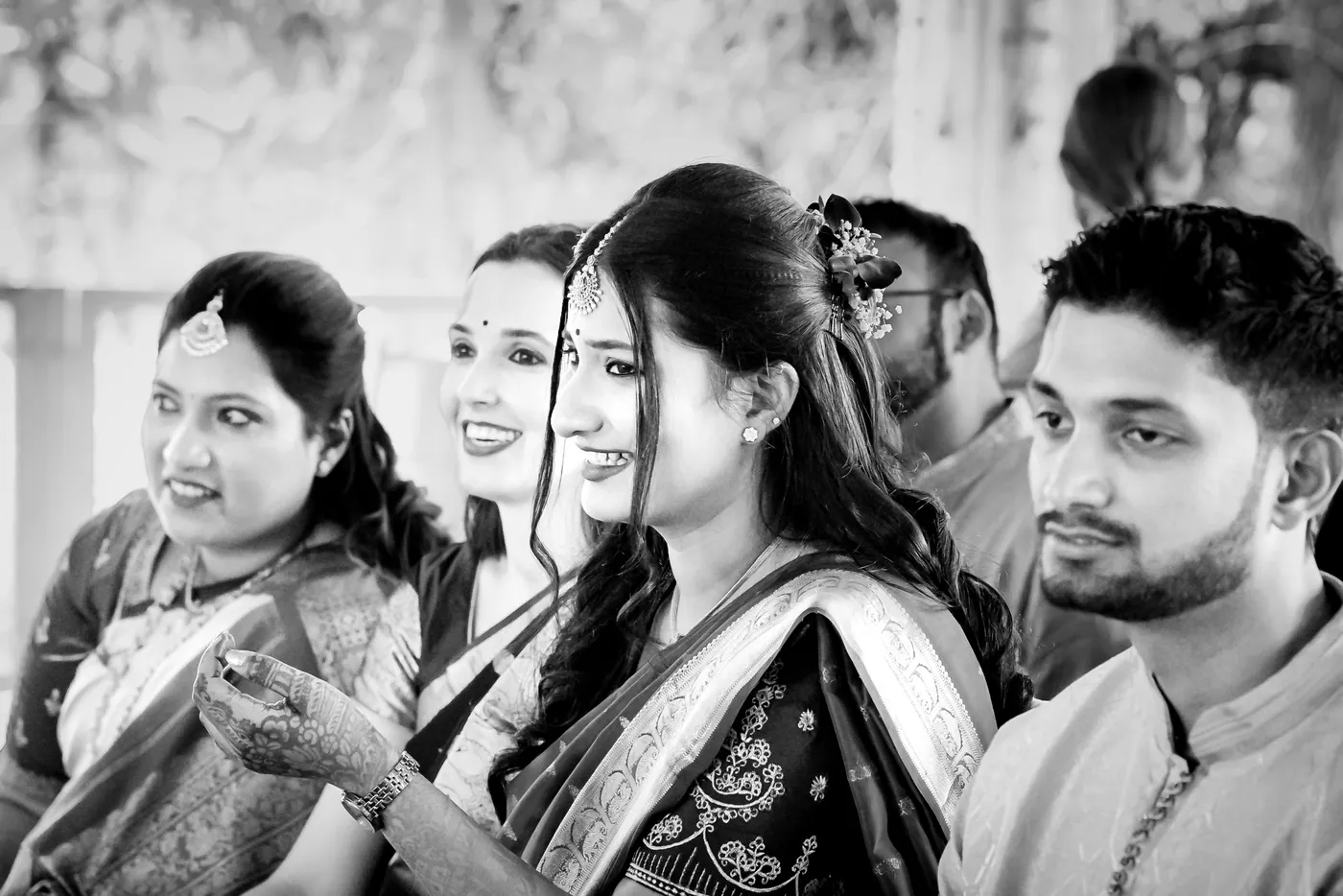 Black and white of friends smiling and sharing a moment during the ceremony