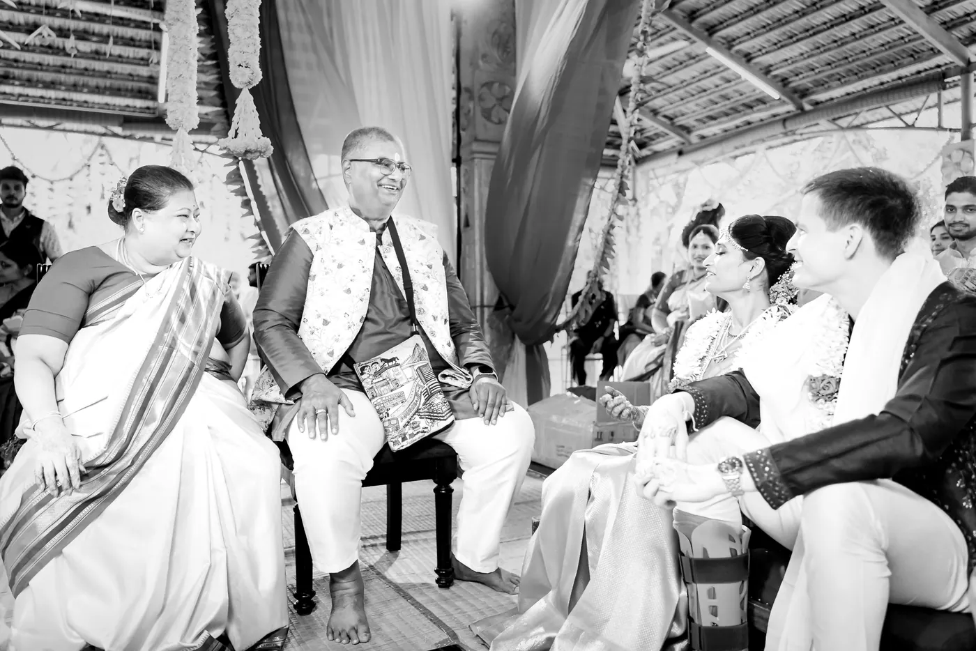 Black and white of an elder and the couple in conversation during the ceremony