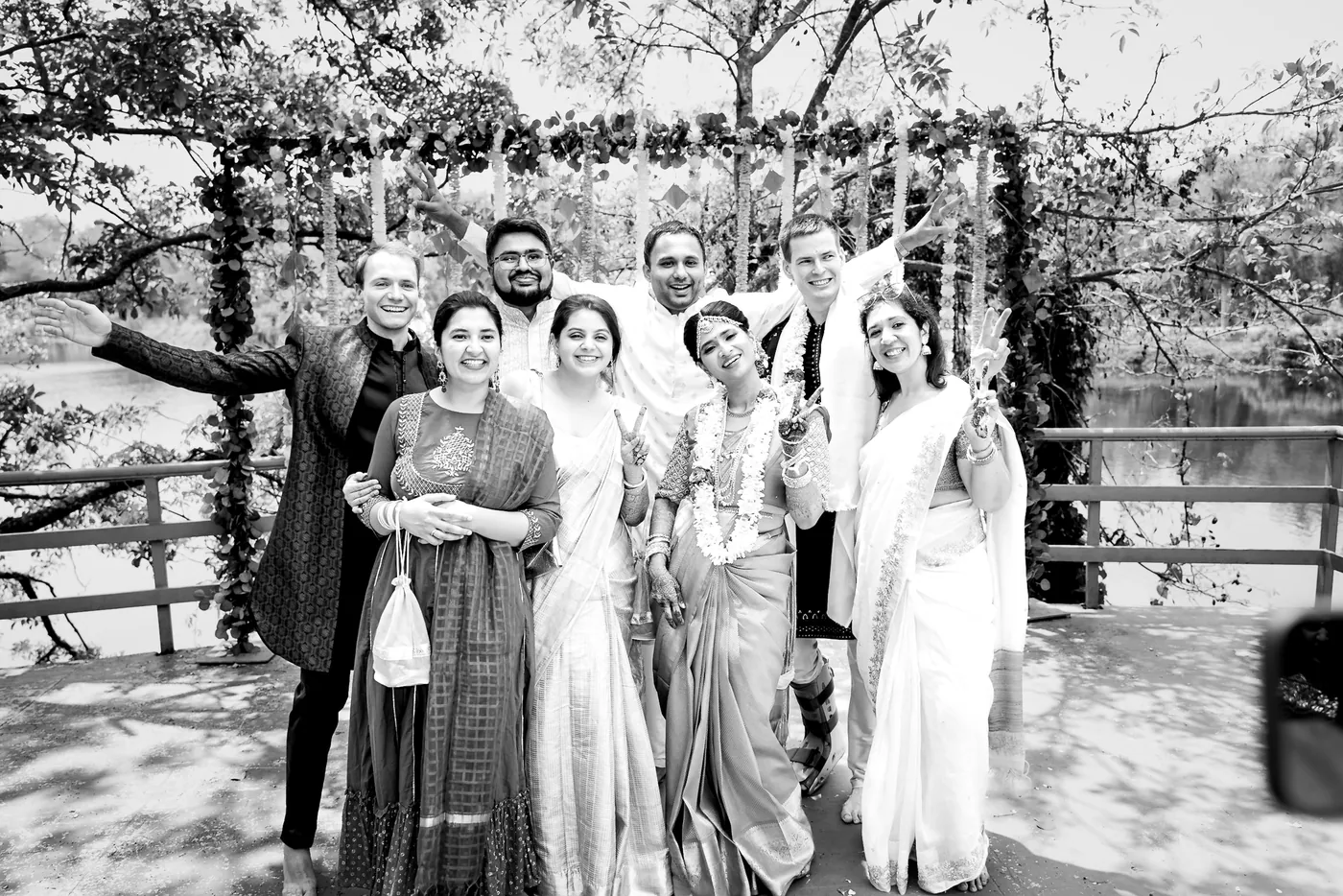Black and white of friends gather on a deck in front of hanging flower strings