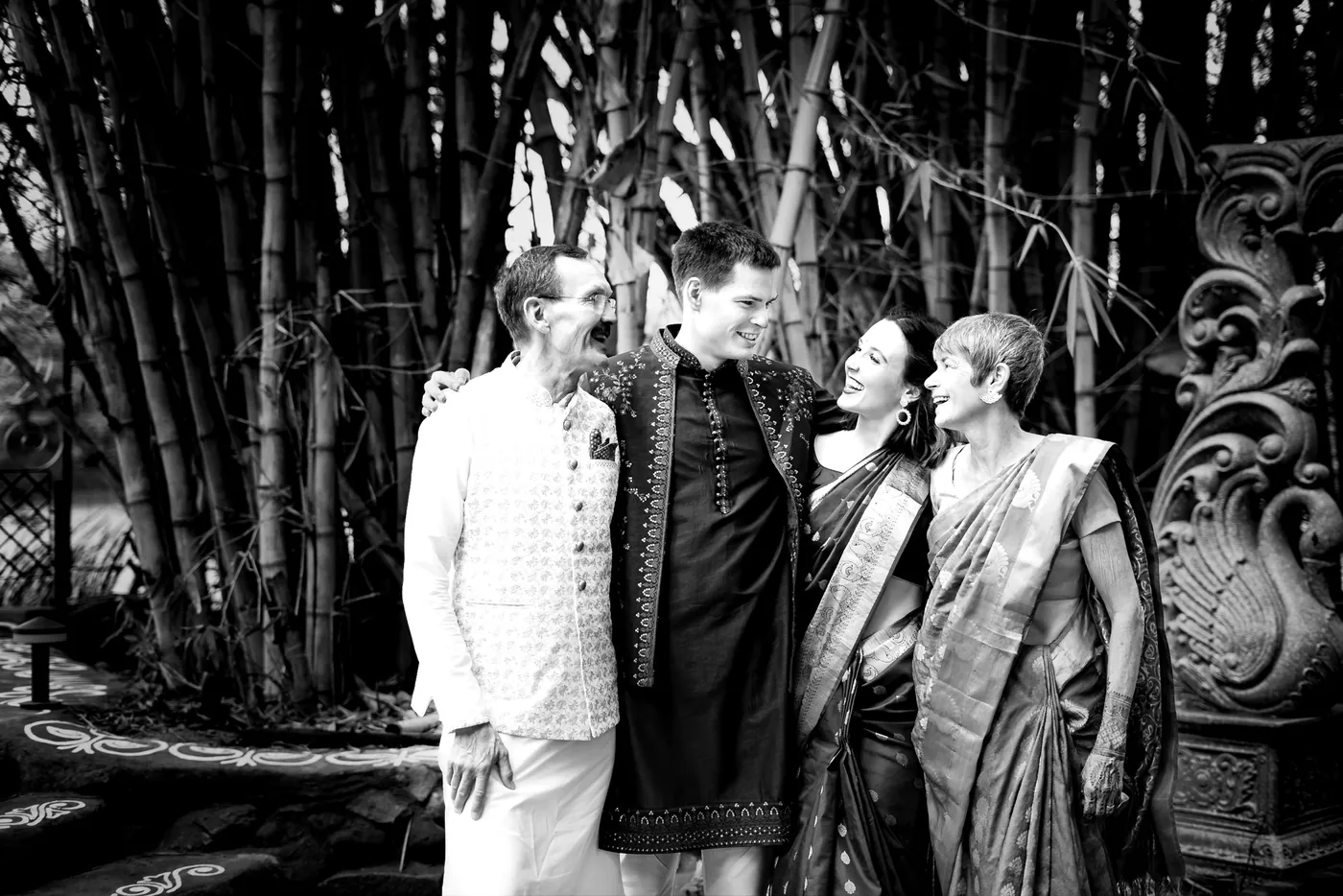 Stefan's father, Stefan, his sister and mother laugh and lean in together in front of bamboo