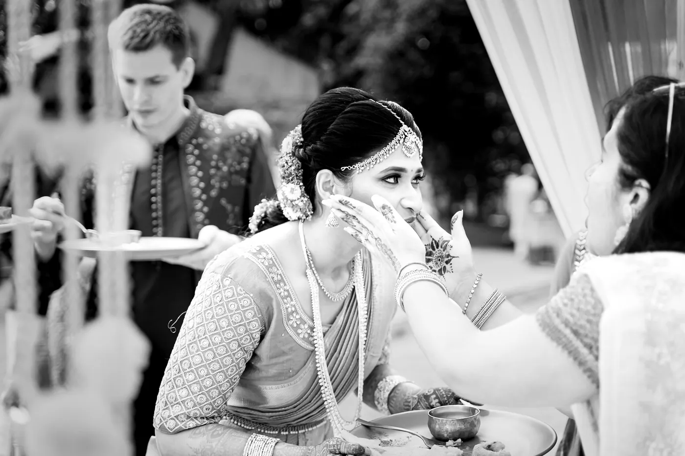 Black and white of Stefan holding a plate while a woman gently touches Medha's face