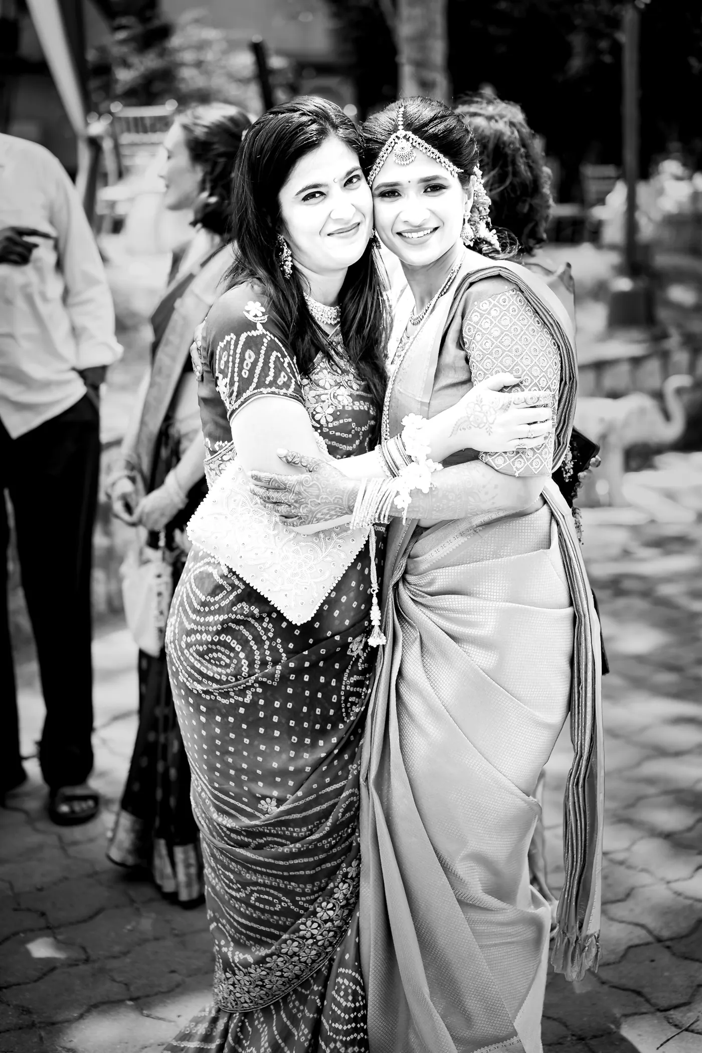 Black and white of two women hugging closely on a paved path