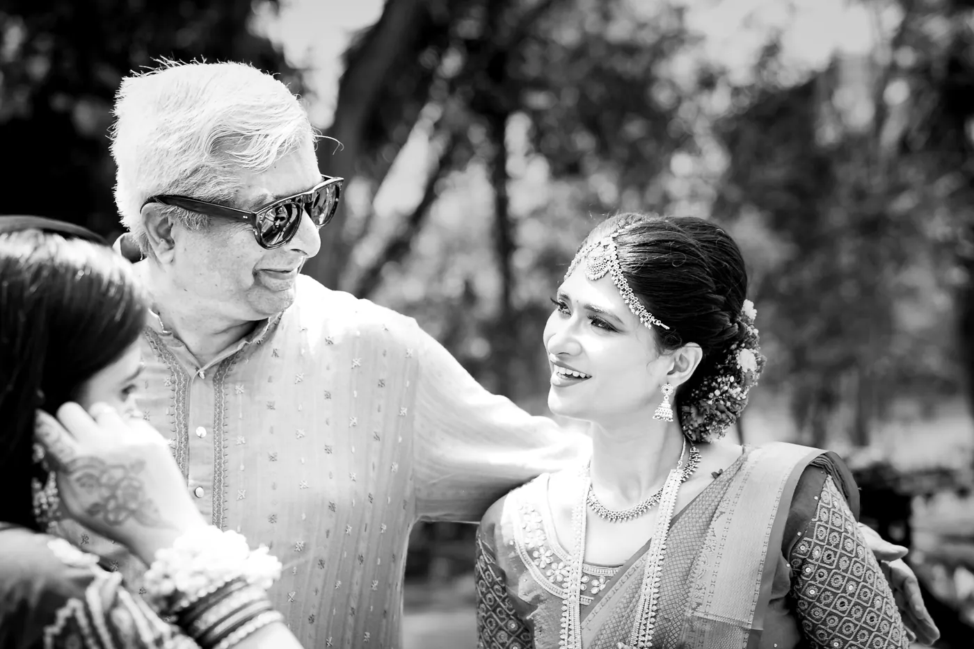 Black and white of an older man in sunglasses leaning close to a smiling woman