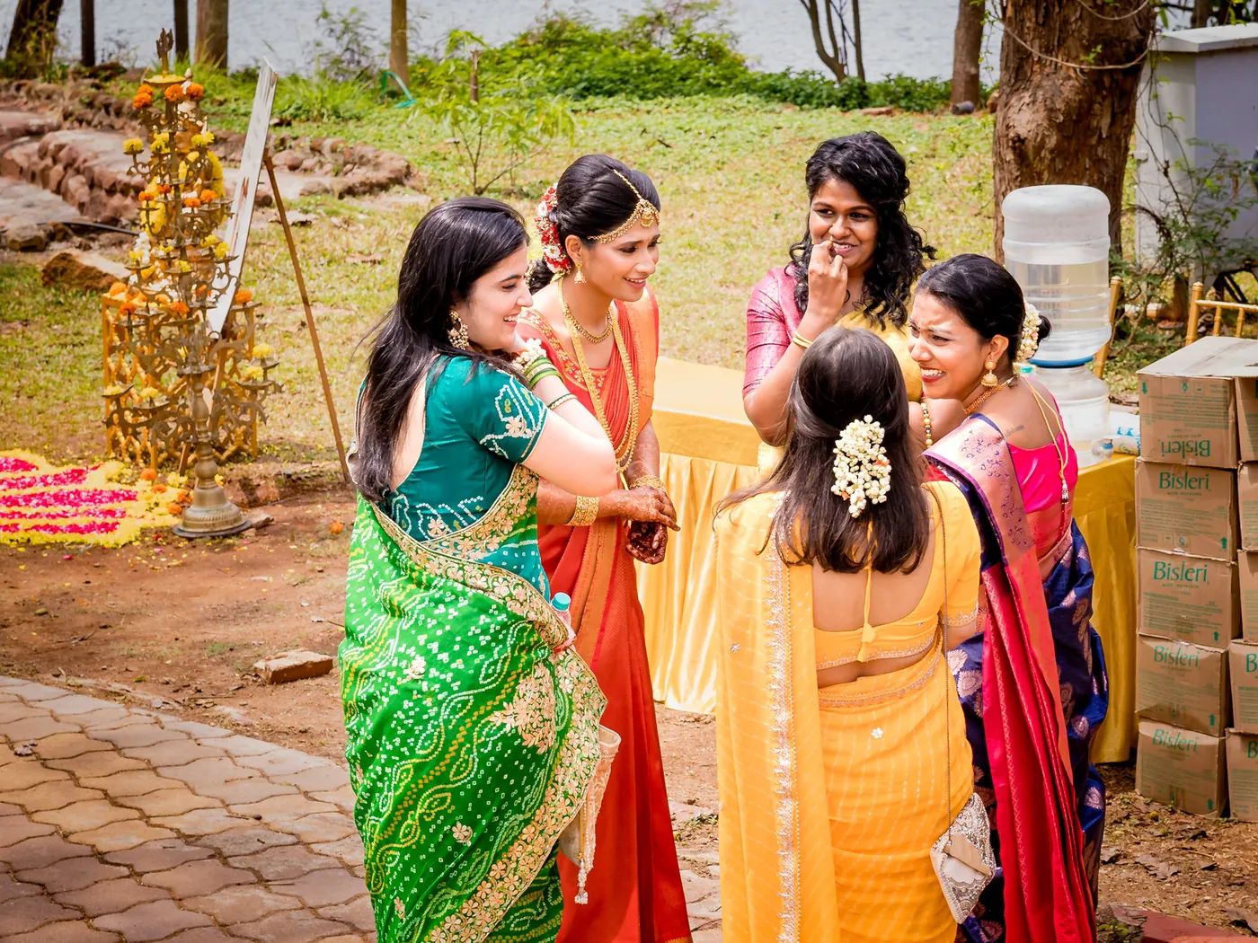 Women in green, orange and yellow saris laugh together on the path