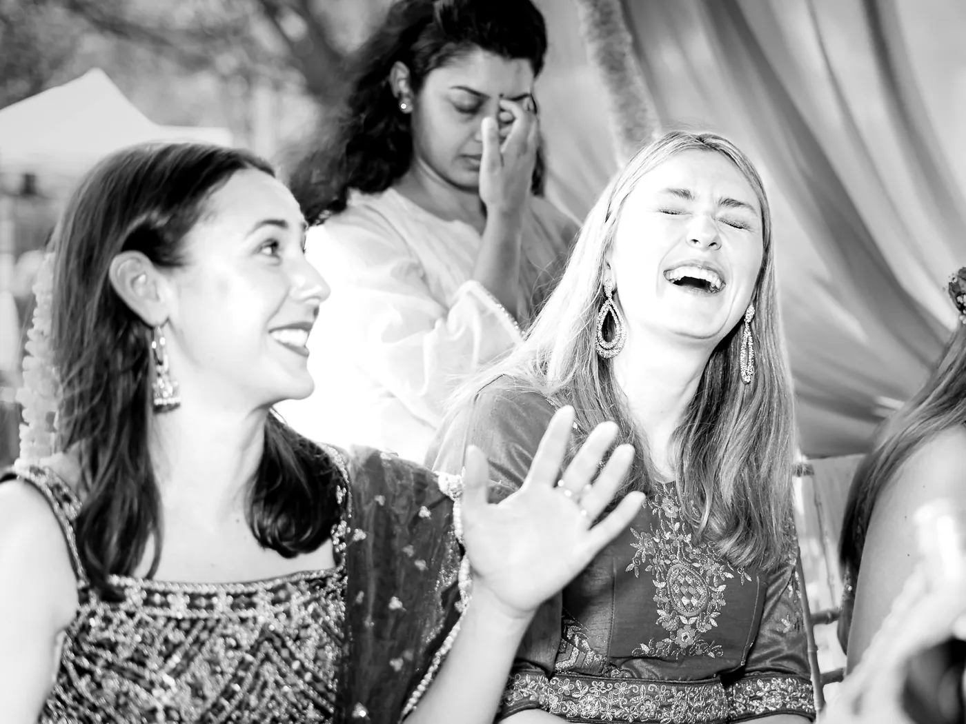 Black and white of friends laughing, one woman wiping tears of joy as another laughs
