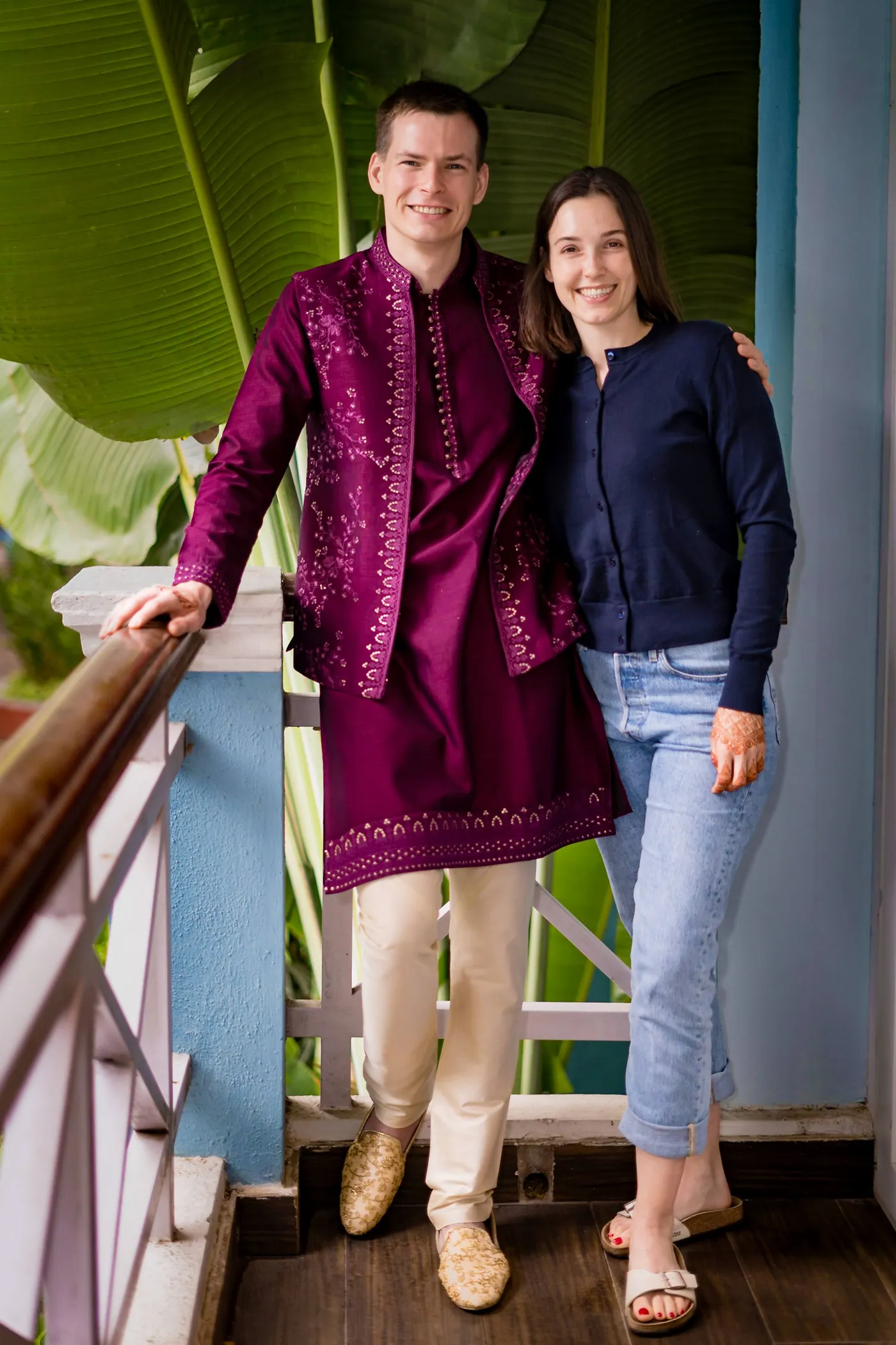 Stefan in a magenta jacket with his sister on a wooden balcony among banana leaves