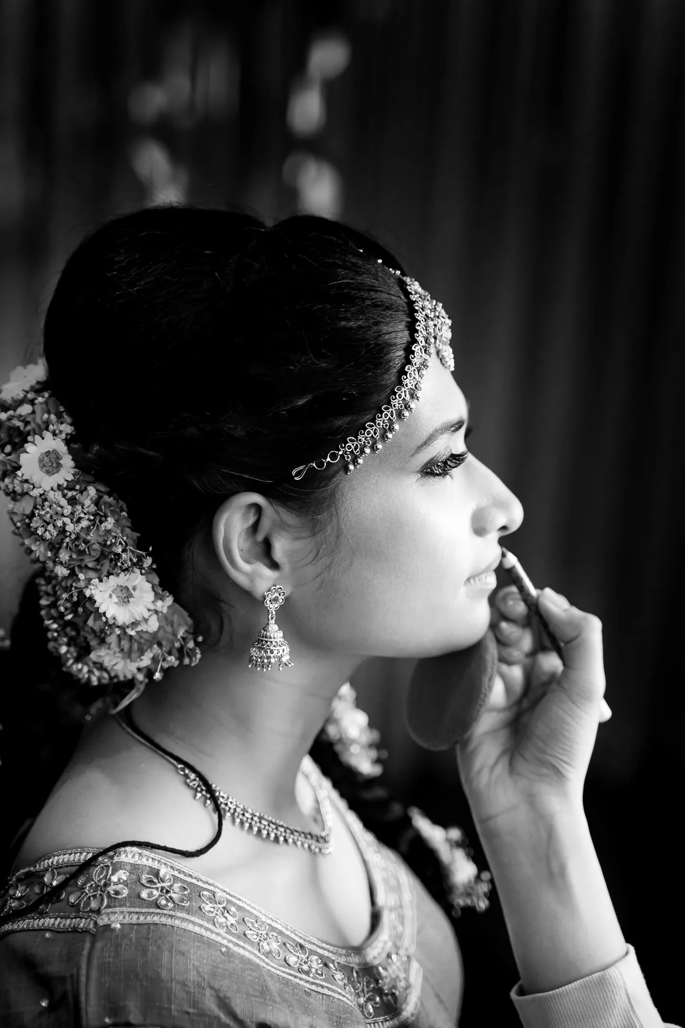 Black and white profile of Medha with a gold headpiece and a hand raised to her lips