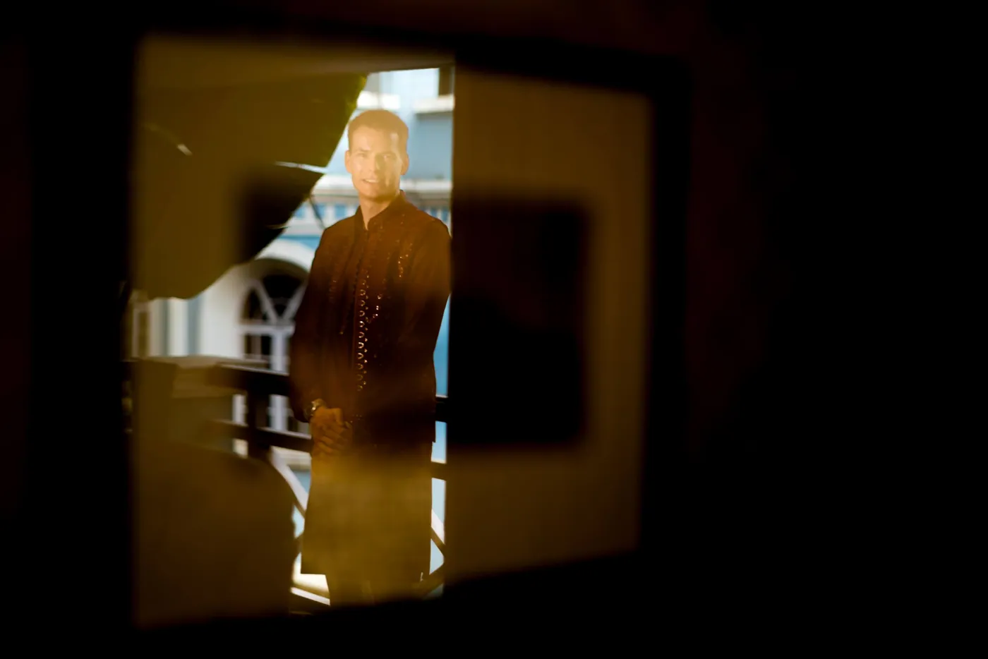 Stefan stands in a glowing doorway frame, seen as a warm silhouette in a dark room
