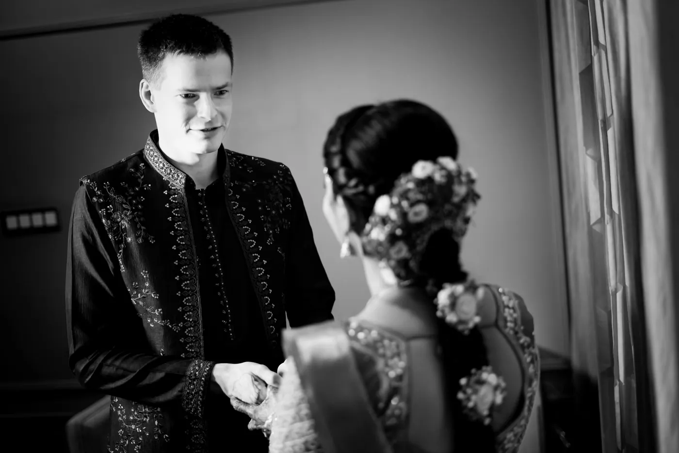 Black and white of Stefan and Medha talking closely, her braided hair with flowers turned toward him