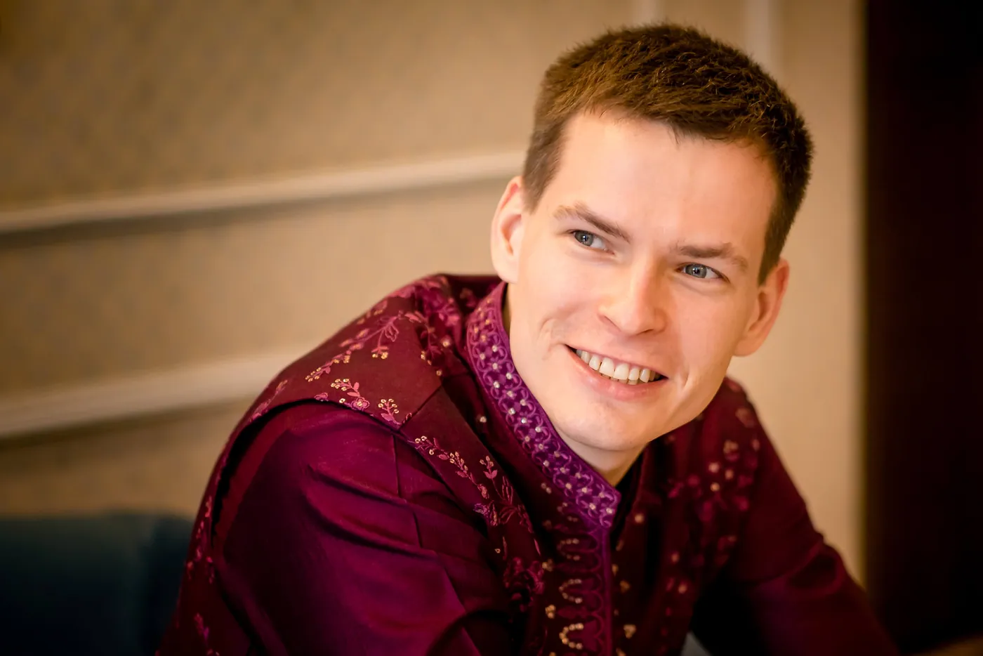 Stefan smiles warmly in a magenta jacket, looking off to the side