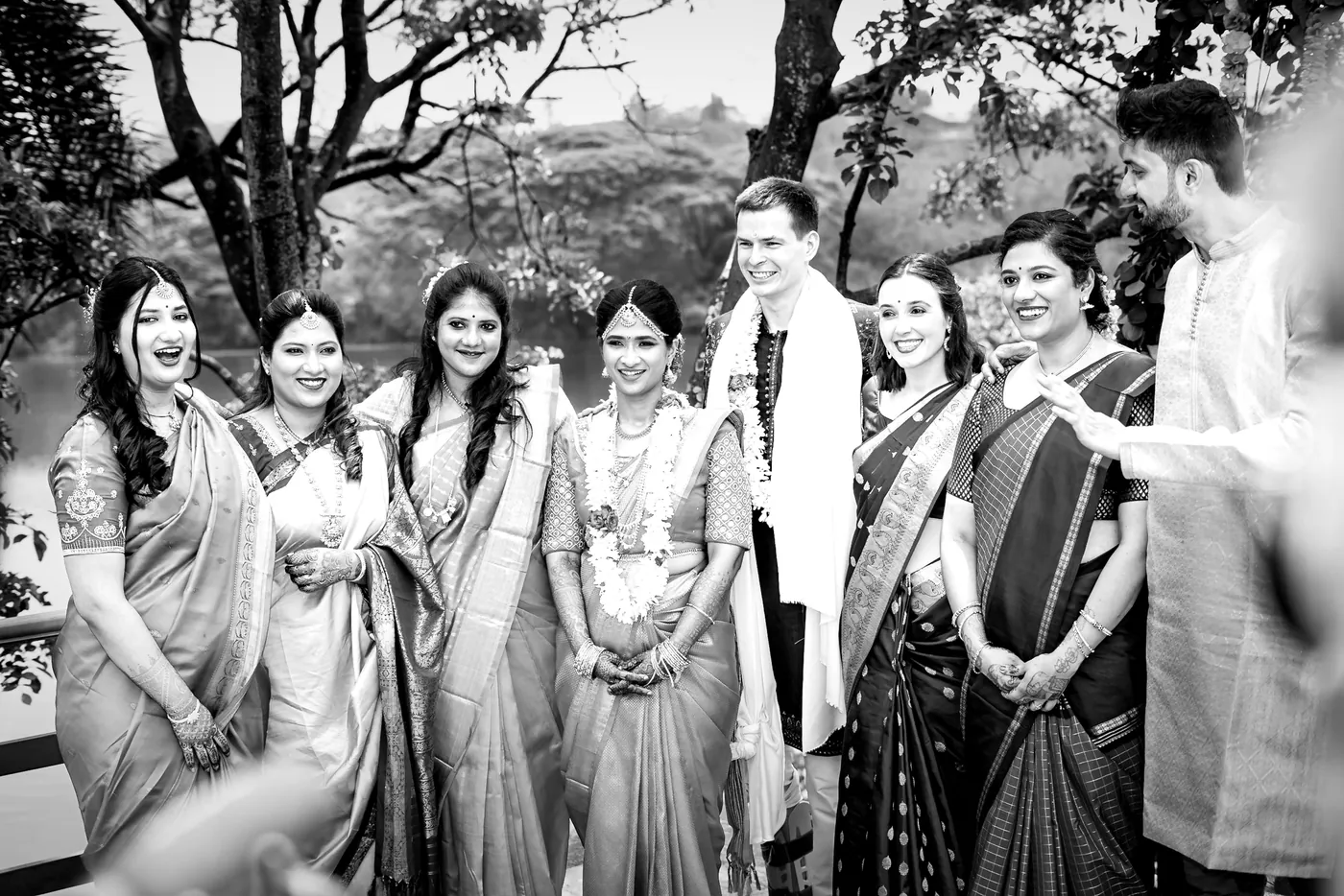 Black and white of friends in saris and kurtas laugh together beside Stefan