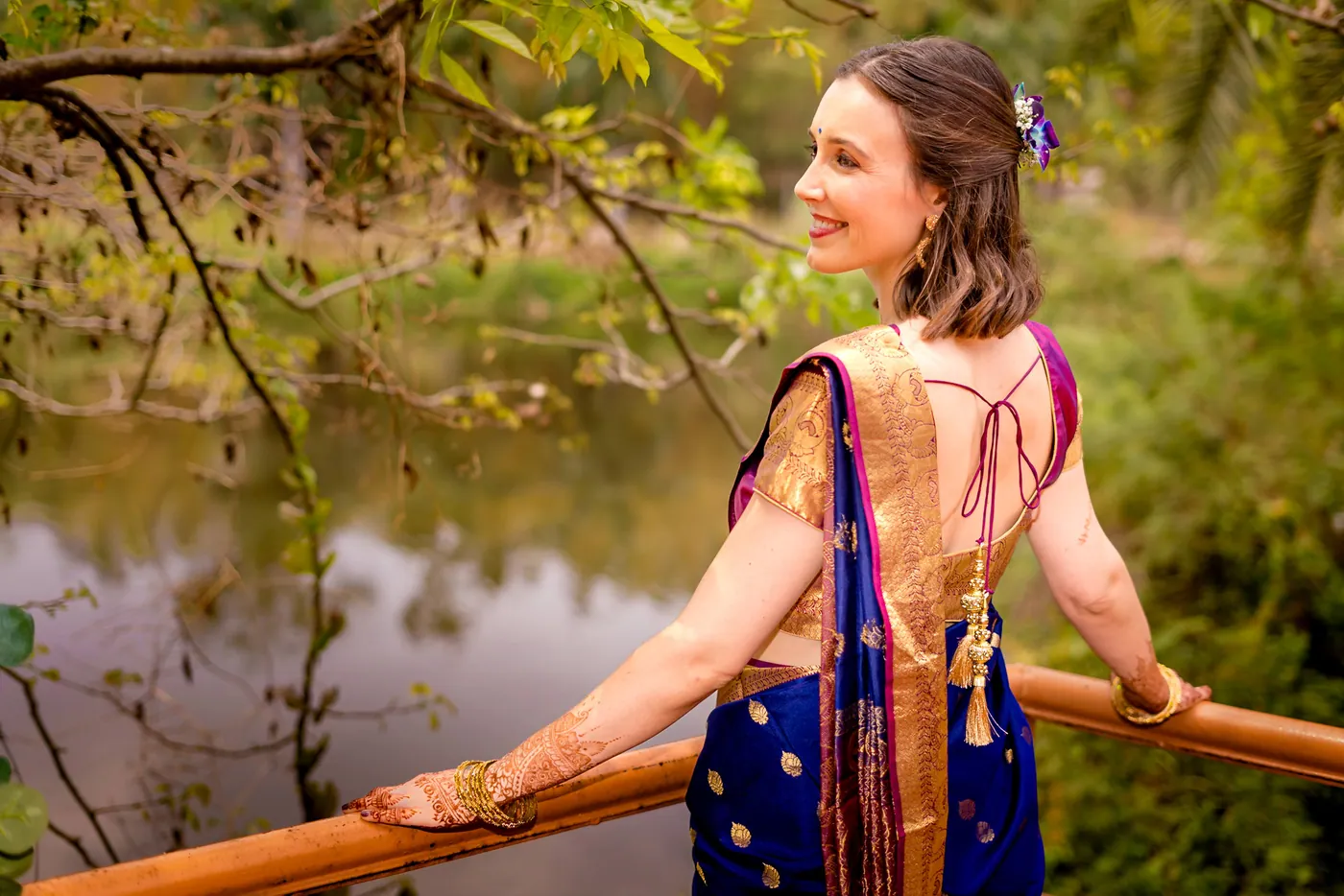 A woman in a blue skirt looks across a lake while standing on a wooden deck