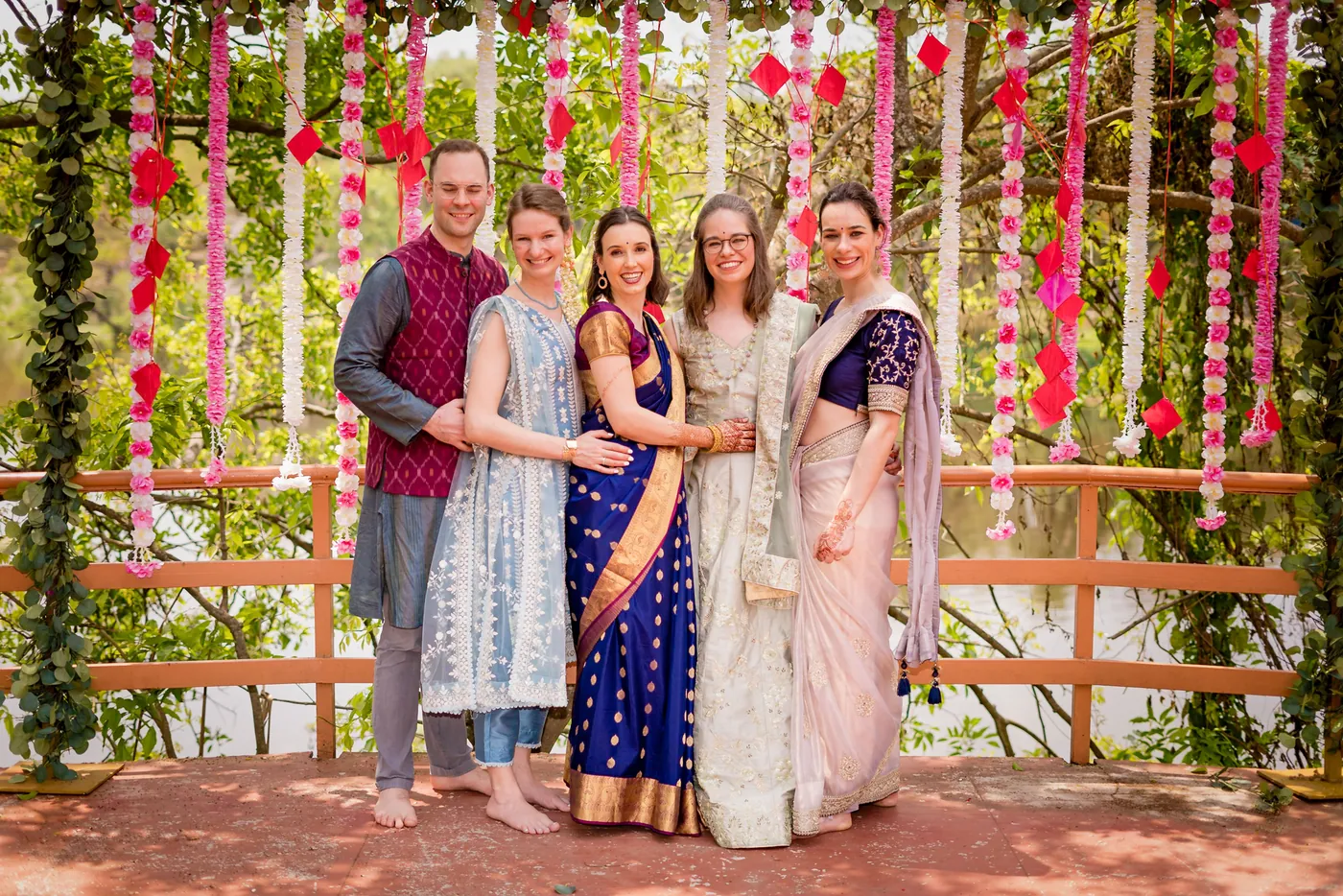 Five friends pose together in front of a flower backdrop